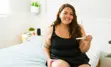 Female-presenting individual smiling and holding pregnancy test